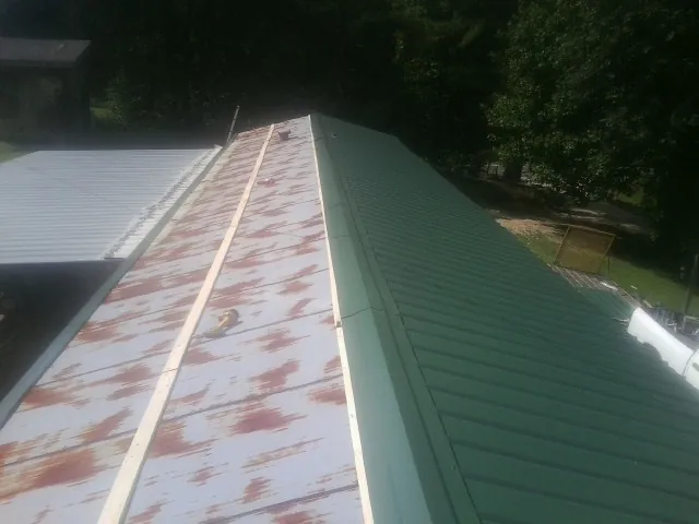 Old rusted panels beside newly installed green metal roofing — Wind Damage Roof Repair by Roofing Brothers in Littlestown