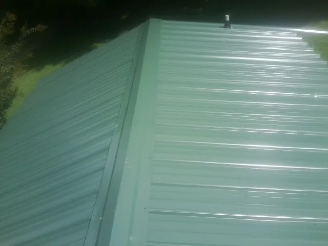New green metal panels meeting at the ridge of a roof — Flat Roof Repair work by our crew in Littlestown