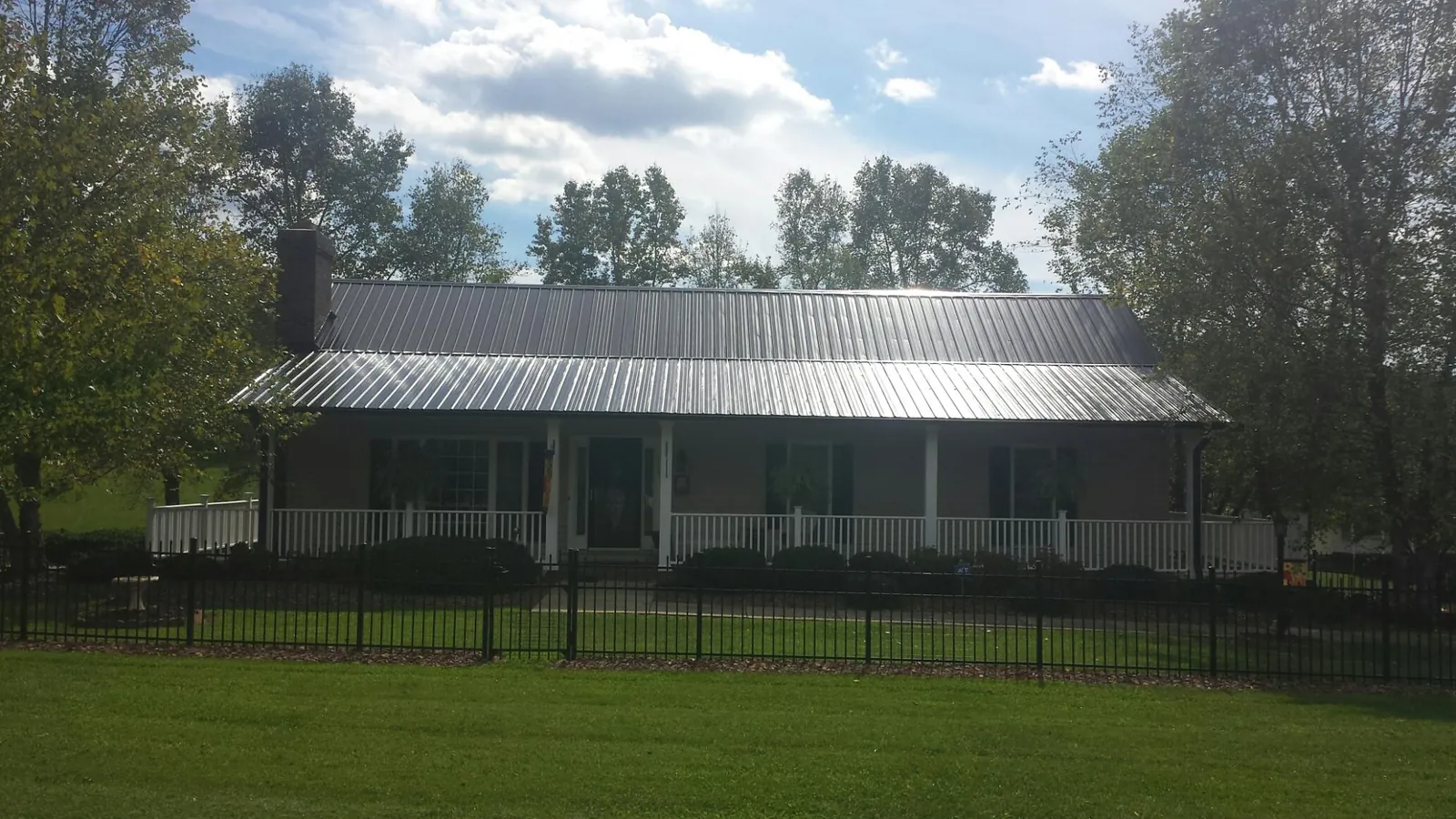 Gray metal roof on a brick ranch with a full width front porch — Gutter Guard Installation work by our crew in Littlestown