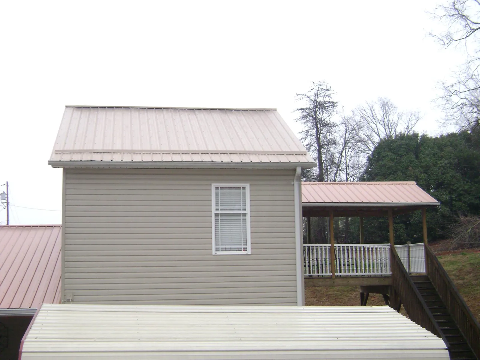 Tan metal roofs on a two story addition and attached porch, from a Roof Replacement job in Littlestown